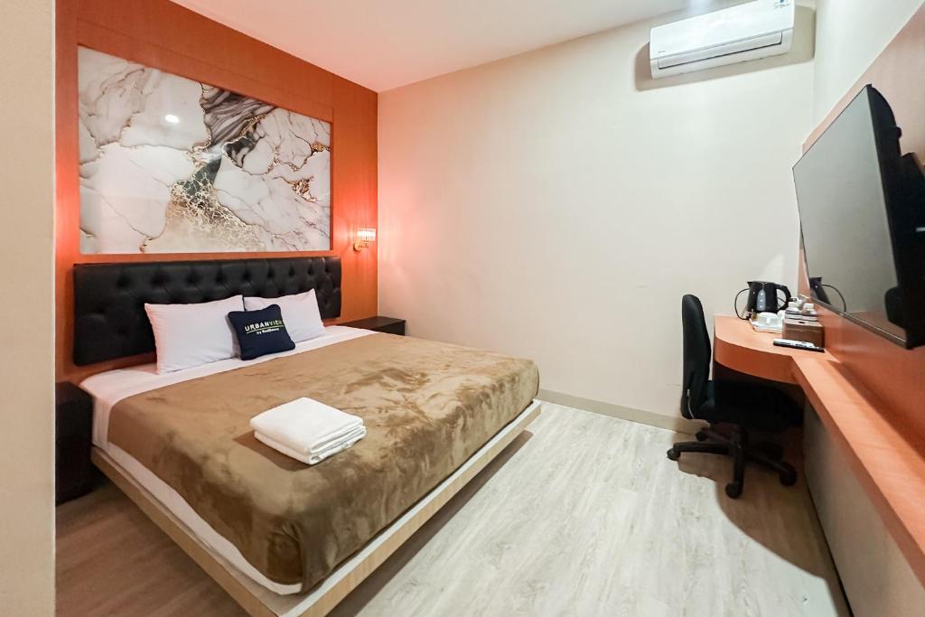 a bedroom with a bed and a desk and a computer at Urbanview Hotel Get Inn Pollux Batam in Batam Center