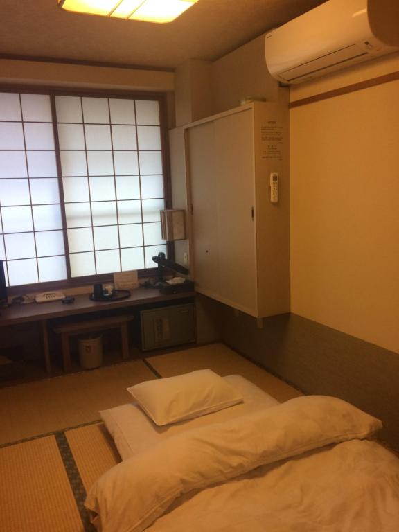 um quarto com uma cama, uma secretária e janelas em Ryokan Meiryu em Nagoya