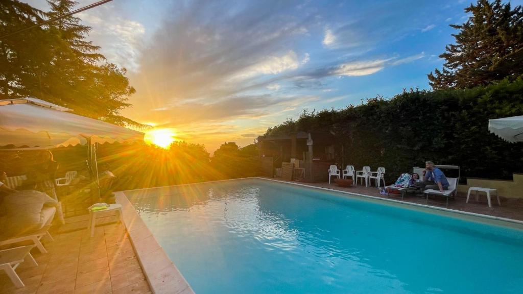 a man sitting on a chair next to a swimming pool at Country House Trevi Umbria Borghetto Vetuliae in Trevi