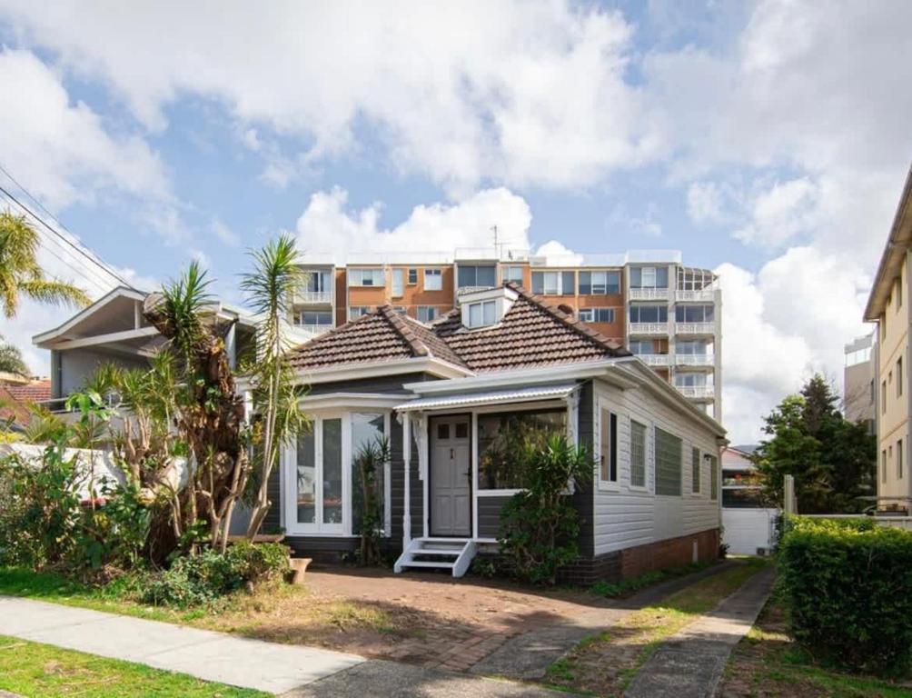 a small white house in front of a building at Cozy Loft Beach House in Wollongong