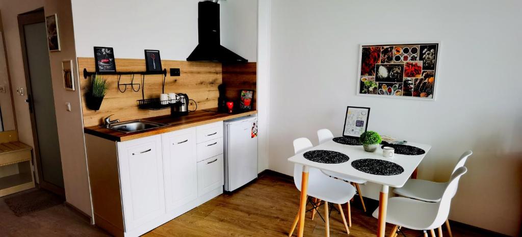 a kitchen with a table and white chairs and a sink at F 207 Primorsko del Sol - просторно студио с кухня in Primorsko