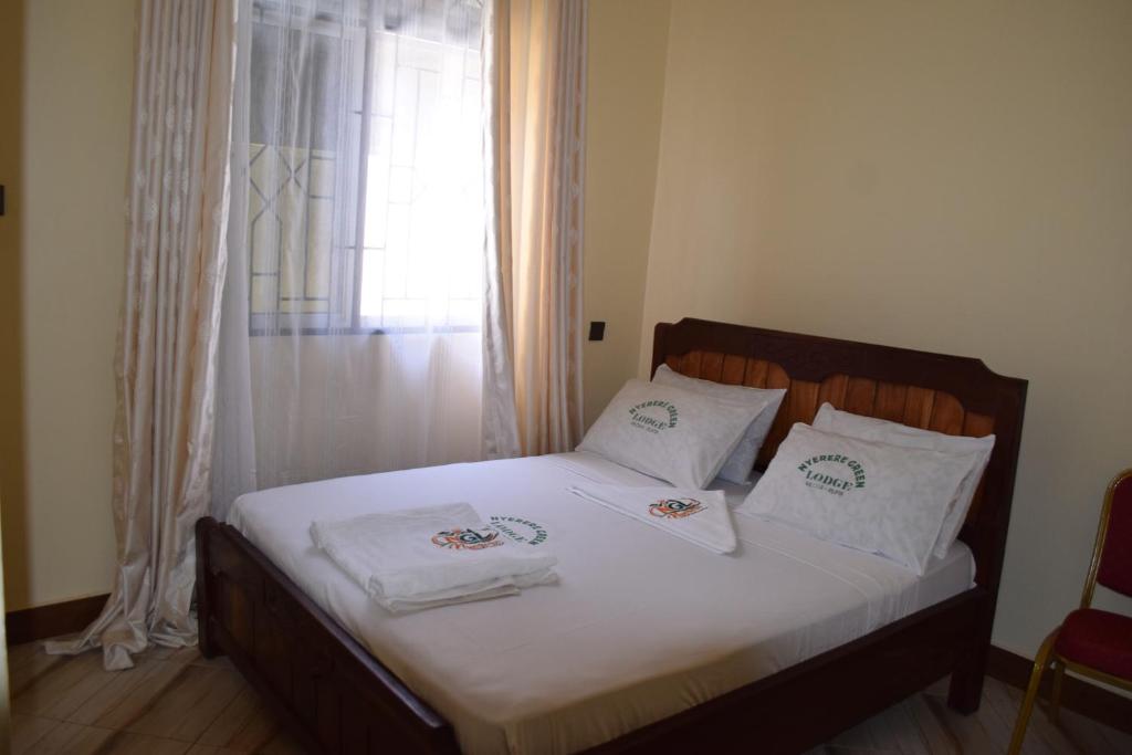 a bedroom with a bed with white sheets and a window at Nyerere Green Lodge in Kwangwazi