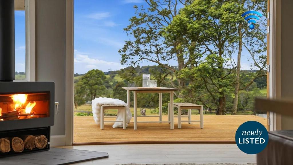 a living room with a fireplace and a table and chairs at Curra Nardie Ranch in Sutton Forest