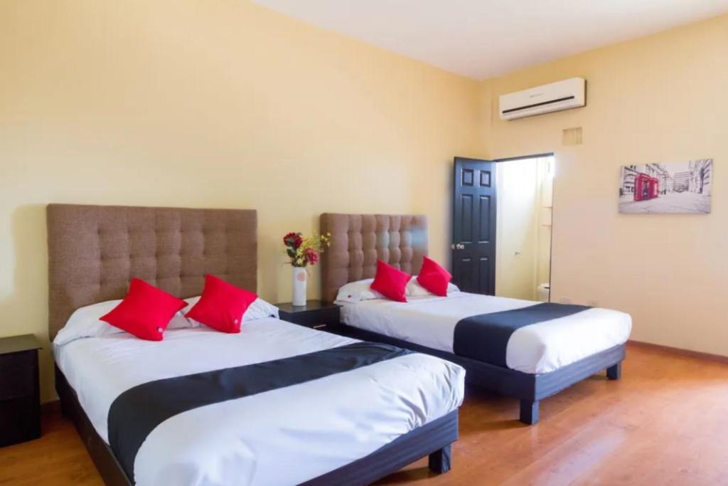 two beds in a hotel room with red pillows at OYO Seoul Garden Apodaca in Monterrey