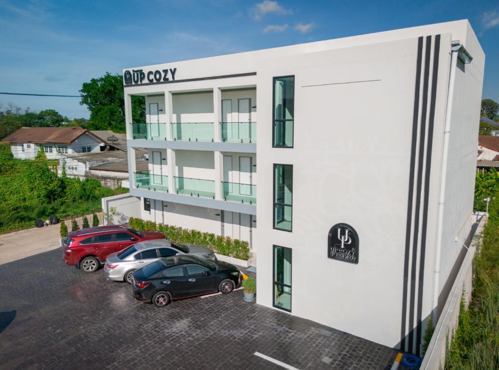 a white building with cars parked in a parking lot at ยูพี โคซี่ in Nakhon Nayok