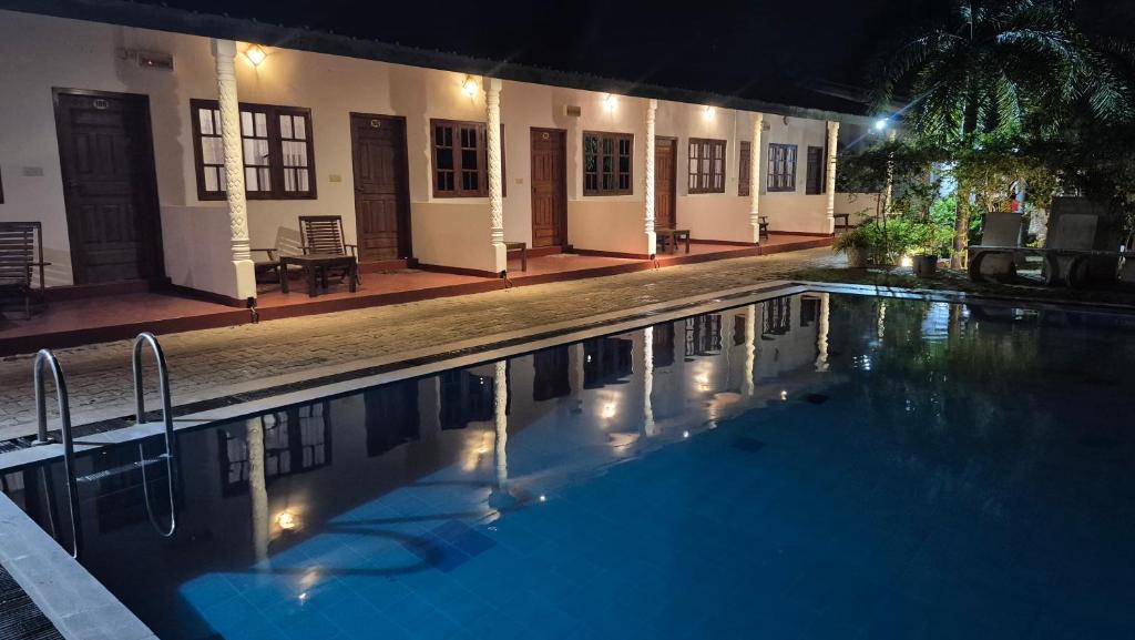 a swimming pool in front of a house at night at Nilaveli Shan Guest in Trincomalee