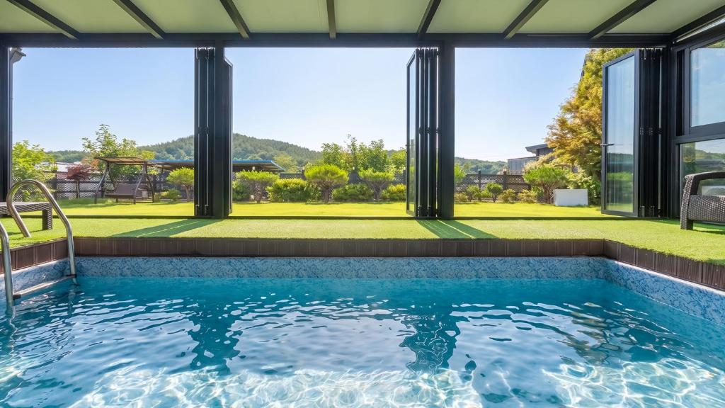 a swimming pool with a view of a house at Yeongheungdo Stay Noc Pool Villa in Incheon