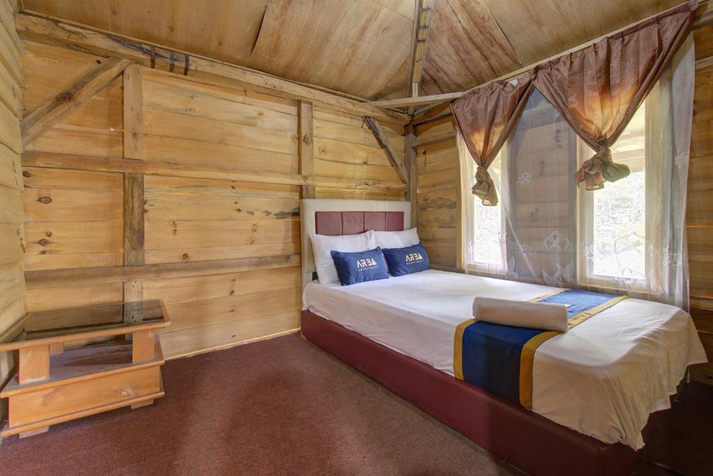 a bedroom with a bed in a log cabin at Kampoeng Regang By BHATARA in Patengan