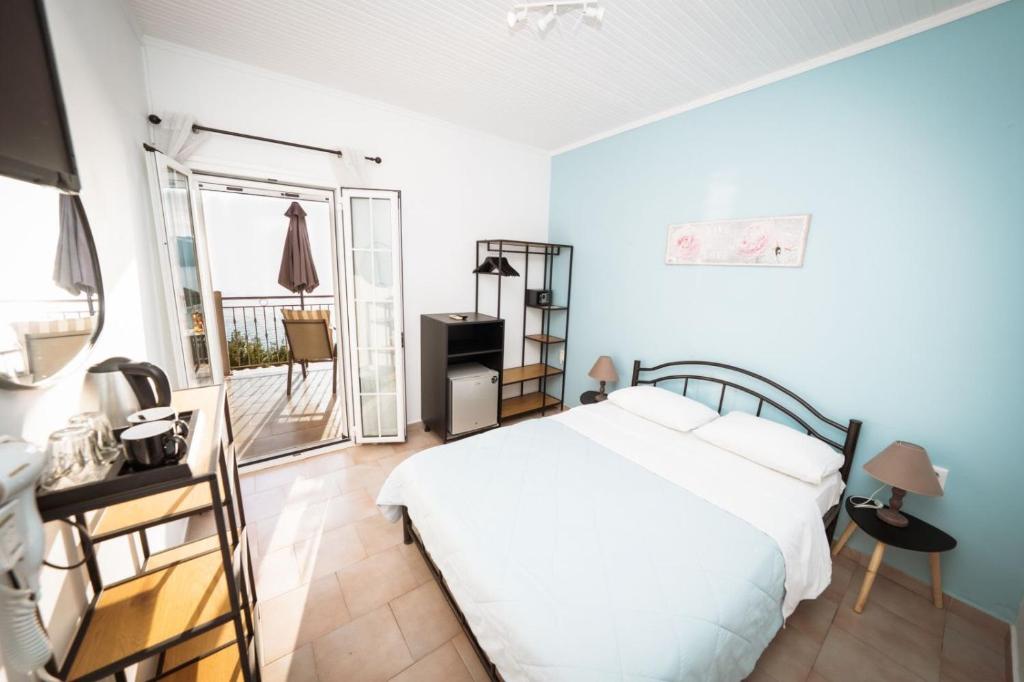 a bedroom with a white bed and a balcony at Bella Vista Apartments in Pelekas