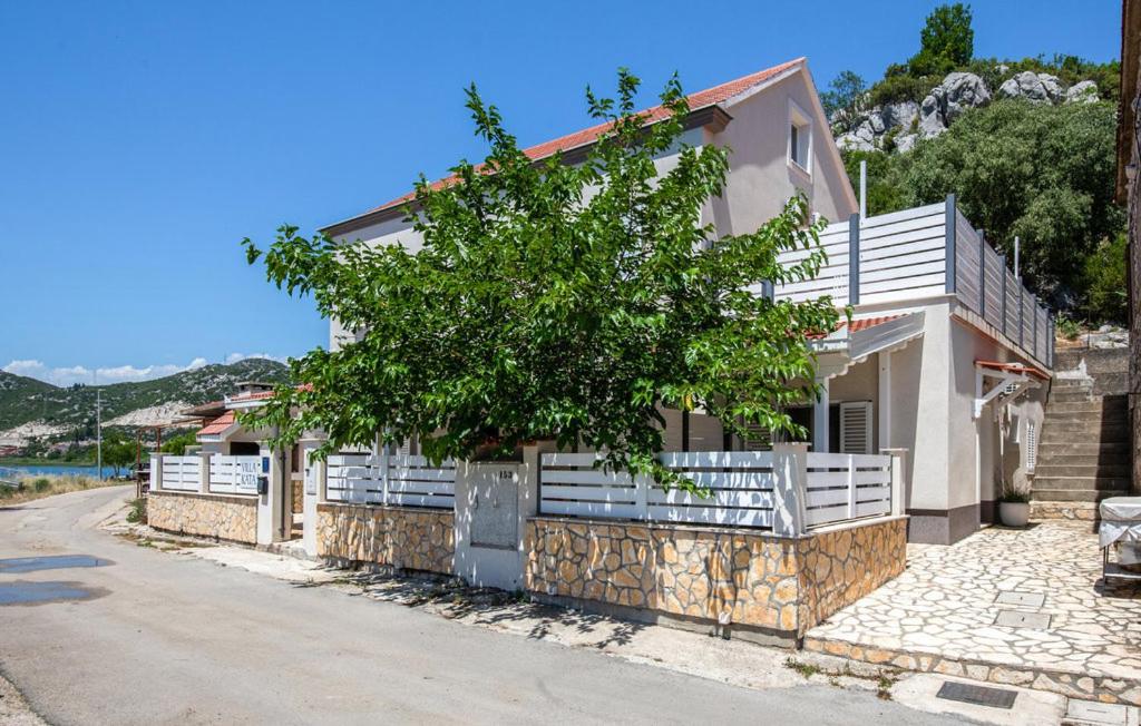a house with a fence and a tree in front of it at First Line Seafront Luxury Apartman Kata in Rogotin