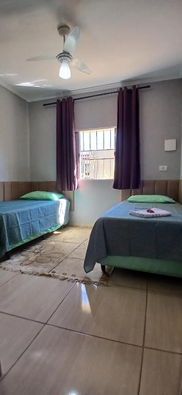 a bedroom with two beds and a window at Quarto Solteiro com TV in Artur Nogueira