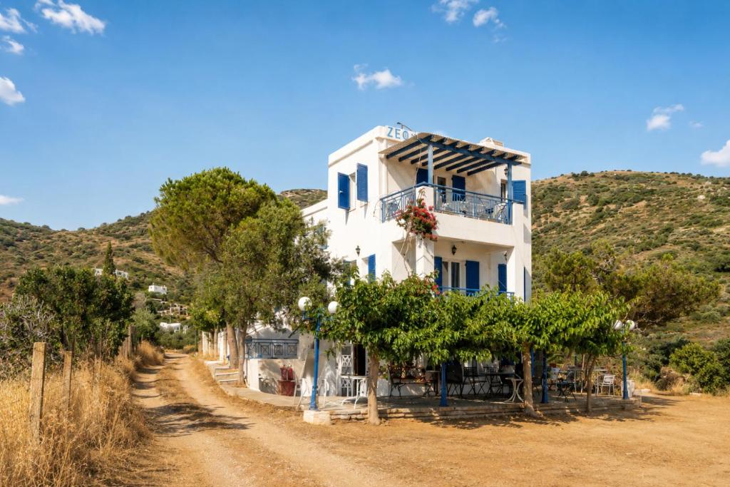 a white building with trees in front of a dirt road at Villa Zefiros in Kipri