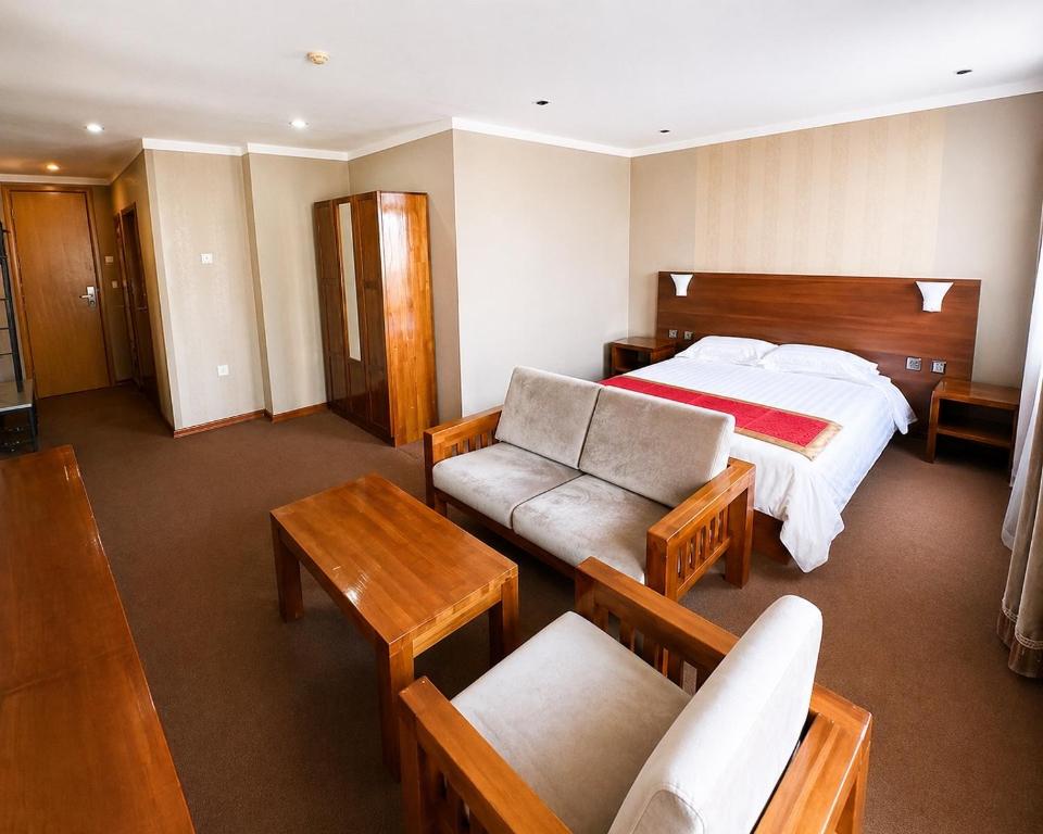 a hotel room with a bed and tables and chairs at Hotel Nomu in Ulaanbaatar