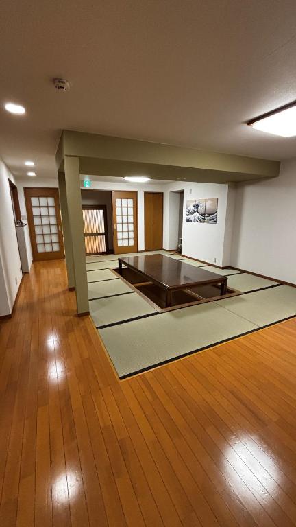 a large empty room with a table on a wooden floor at さくらやゲストハウス in Tokushima