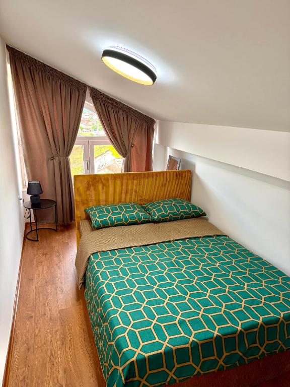 a bedroom with a bed with a green comforter at COSMOS Panorama Apartments in Prilep