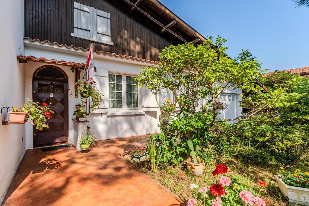 a house with a flag and flowers in front of it at Dunevoile chambre d'hôtes in Biscarrosse-Plage