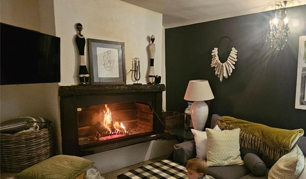 a living room with a fireplace and a child sitting on a couch at The Lily House Hermanus - Central Private Cottages in Hermanus