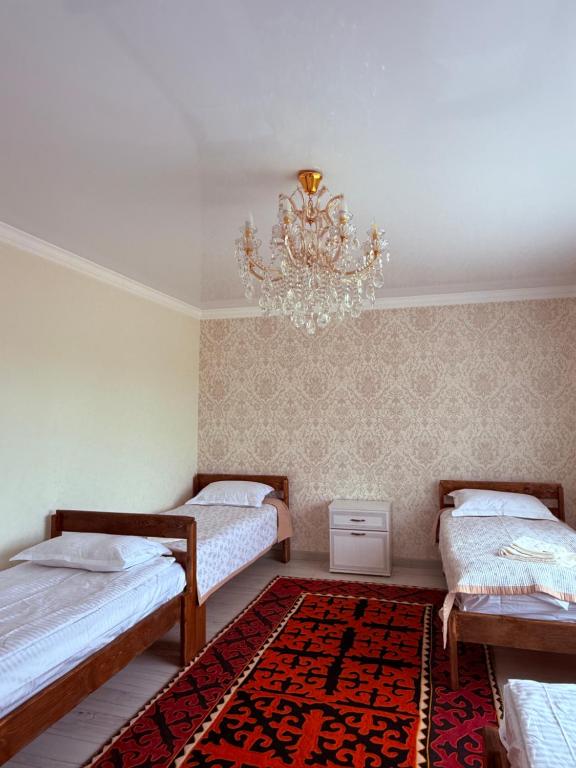 a bedroom with two beds and a chandelier at Erkaiym Guest house in Bokonbayevo