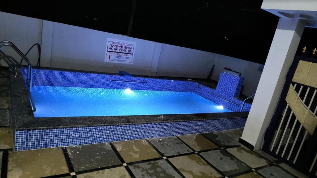 a swimming pool with blue tile around it at Ros Villa in Vikārābād