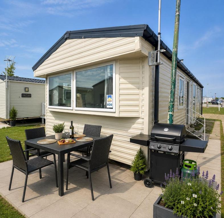 a tiny house with a table and a grill at Luxury Family Caravan St Osyth Beach Clacton on Sea in Saint Osyth