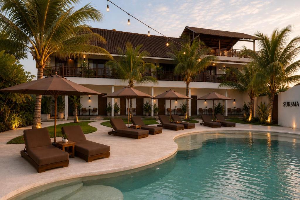 a resort with a pool and lounge chairs and a building at Suksma Guesthouse in Canggu