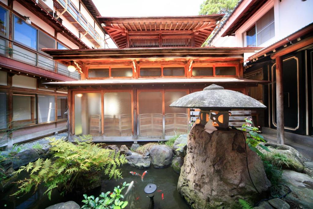 uma casa com um lago em frente a um edifício em Yudanaka Seifuso em Yamanouchi