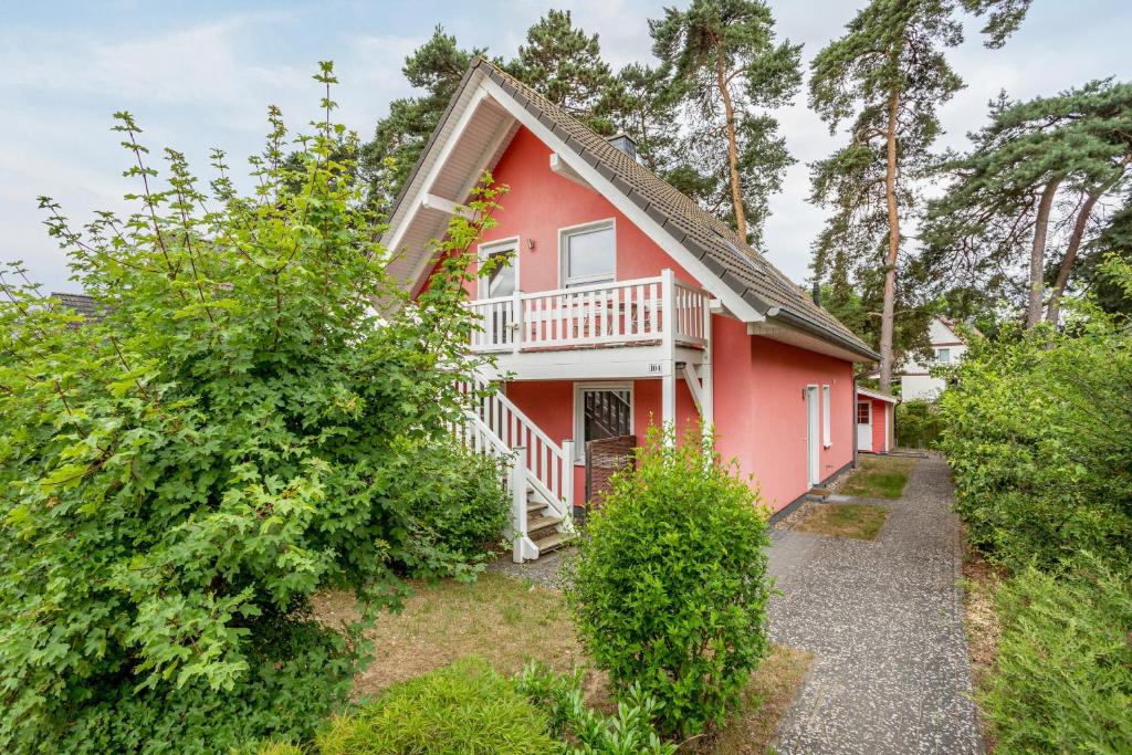 a red house with a balcony and trees at Haus K 104 in Röbel