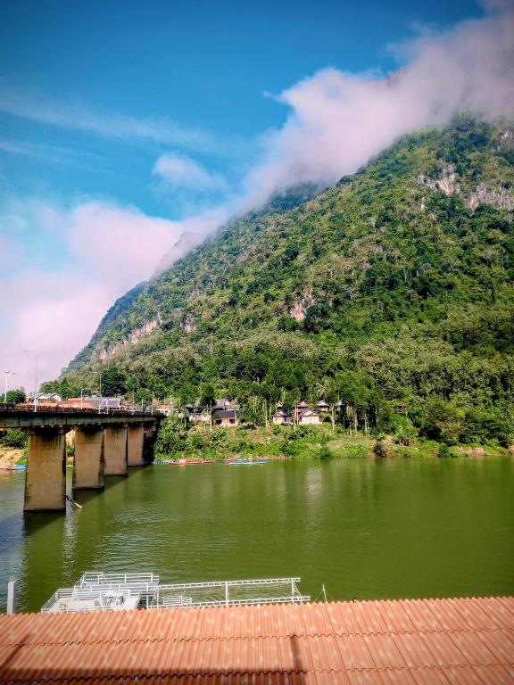 a boat on a river next to a mountain at Nongkhaiw Hostel in Nongkhiaw