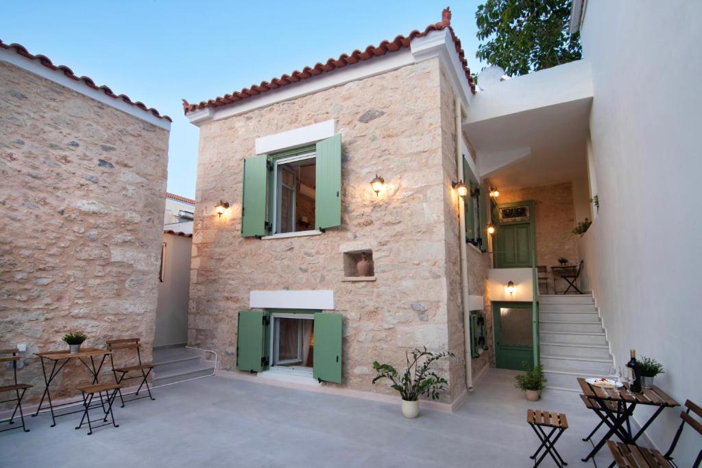 a courtyard of a house with green shutters at Amalthea Guest House in Egina