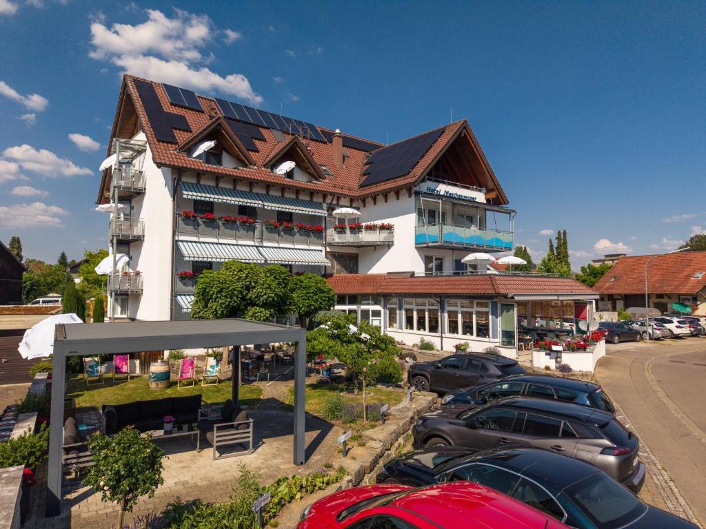 a large building with cars parked in a parking lot at Hotel Meschenmoser in Langenargen