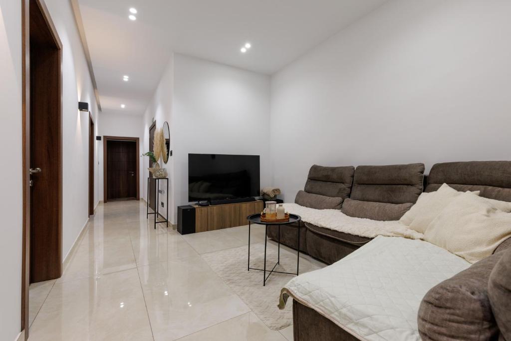a living room with a couch and a television at Bayleaf Coastal Apartment in Marsaxlokk