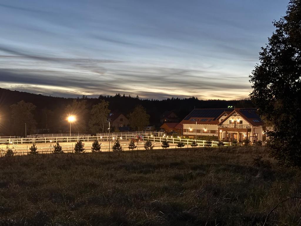 a house in a field at night with a fence at Agroturystyka Myślinów - Black Horse Bar&Grill in Męcinka