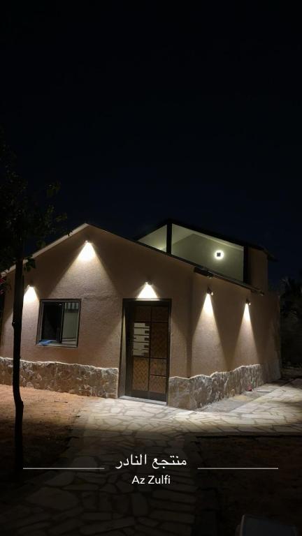 a house with lights on the side of it at night at منتجع النادر الريفي in Az Zulfi