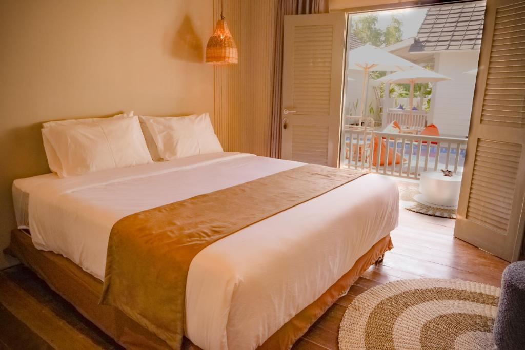 a bedroom with a large bed and a balcony at Hu'u Beach Front Hotel in Gili Trawangan