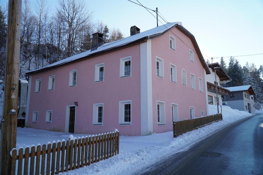 a pink building with a fence in the snow at S'Platzl in Wenns