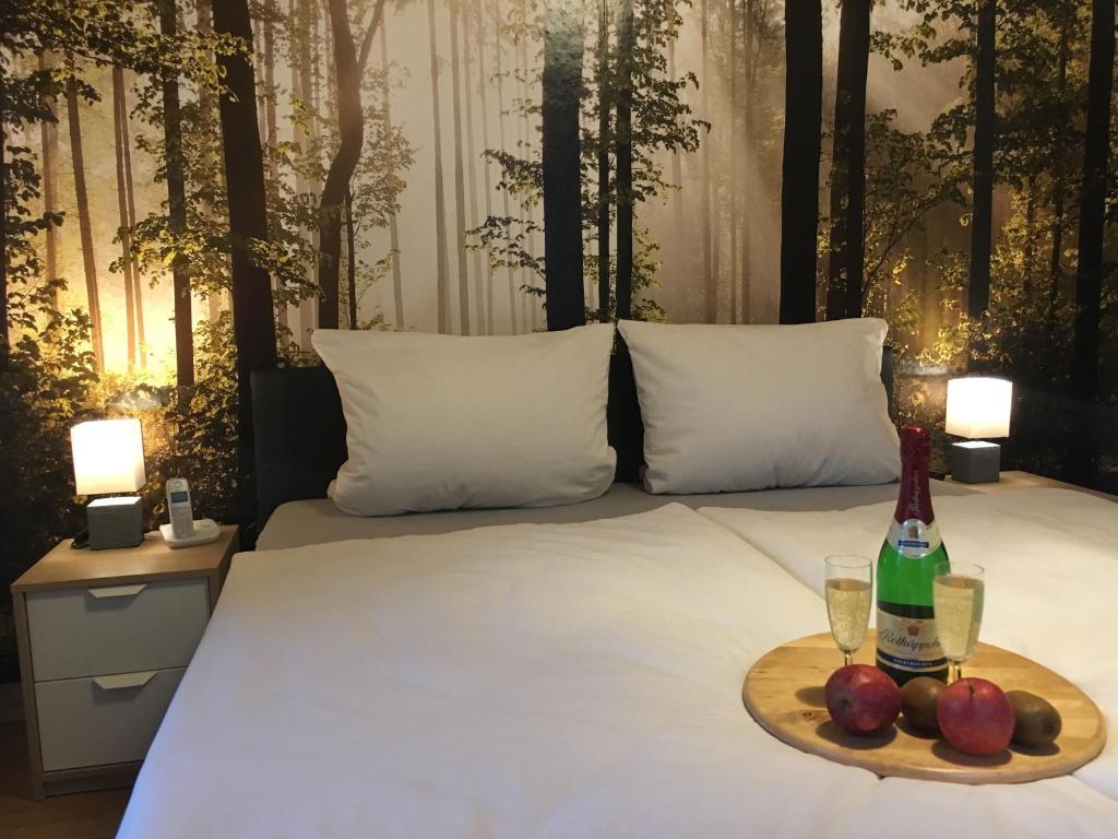 バートライヘンハルにあるHaus Annelieseのベッドの上にワイン1本とフルーツを用意したトレイ