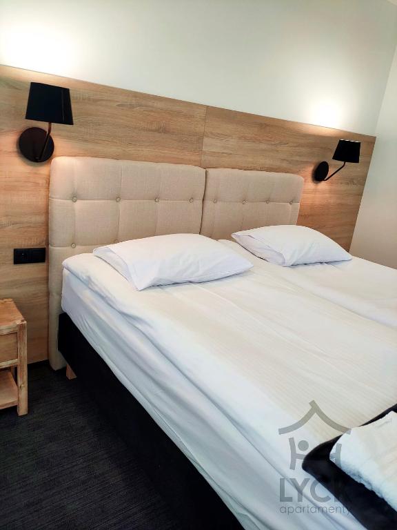 a large bed with white sheets and pillows at Lyck Aparthotel in Ełk