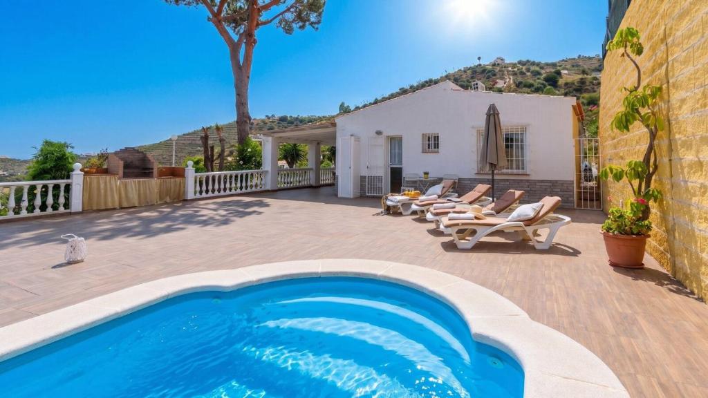 a backyard with a swimming pool and chairs and a house at Elsa Torrox by Ruralidays in Torrox