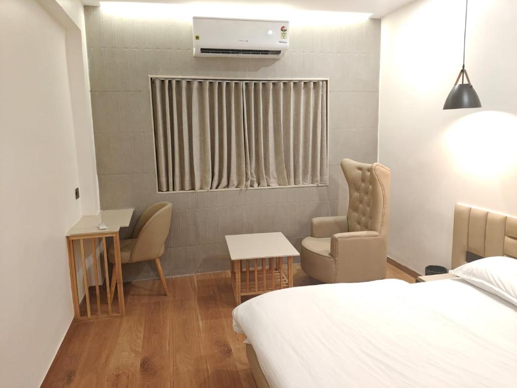 a bedroom with a bed and two chairs and a window at Hotel Krishiv- Sanand in Sānand