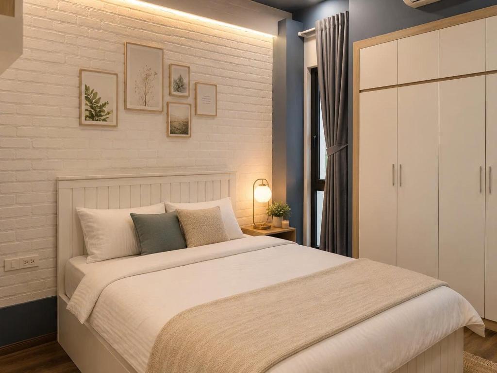 a bedroom with a large bed and a white wall at JOY APARTMENT TAY HO in Hanoi