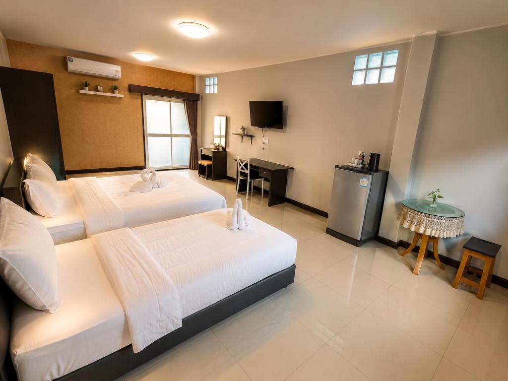 a hotel room with two beds and a television at Ruen Aiyara Apartment in Nakhon Ratchasima