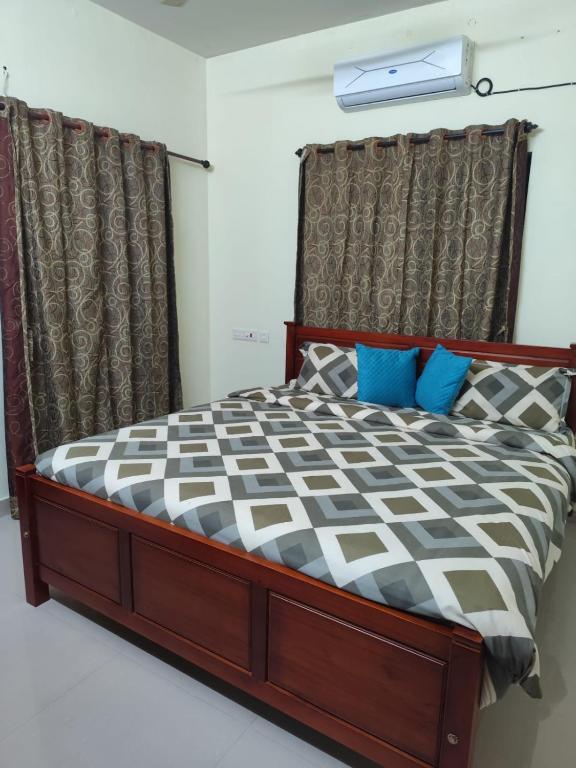 a bedroom with a large bed with blue pillows at Hotel Suncity Villa in Trivandrum