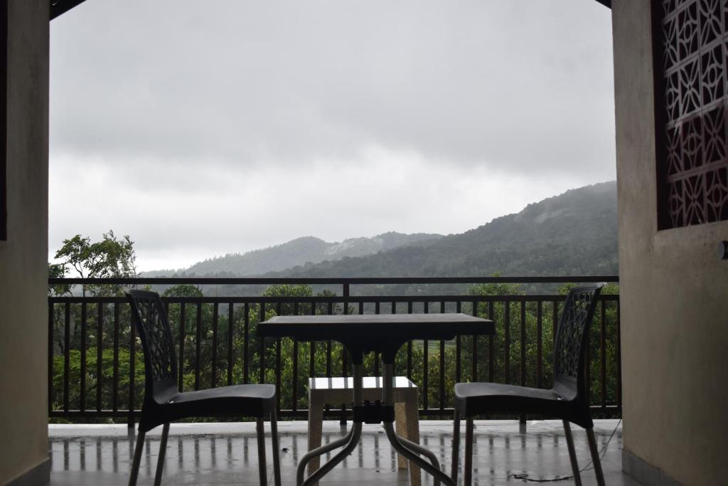 a table and chairs on a balcony with a view at Naisarga hill view homestay in Somvārpet