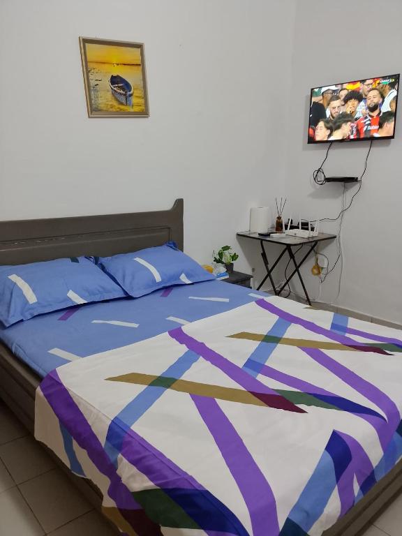 a bedroom with a bed with a blue and purple comforter at Js Immobilier in Abidjan