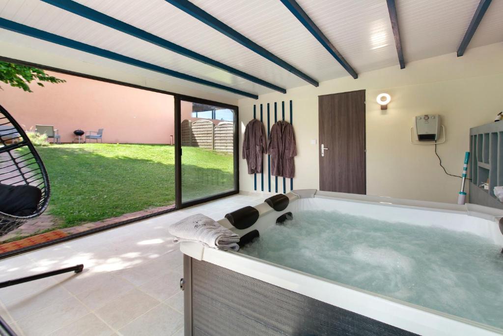 a jacuzzi tub in a room with a large window at Gîte Ressources - Jacuzzi in La Frenaye
