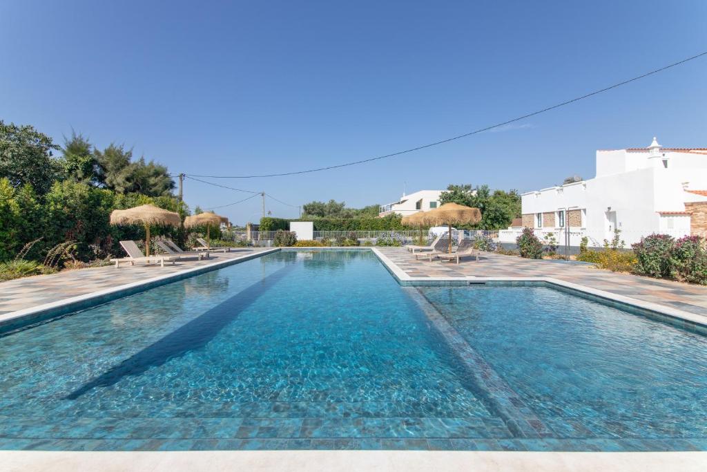 a large swimming pool with chairs and umbrellas at Vilas Salero in Moncarapacho