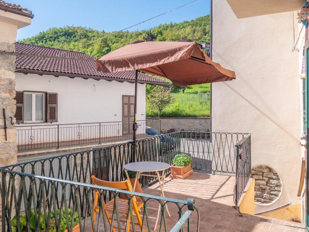 a balcony with a table and an umbrella at Rosano 76 in Cabella Ligure