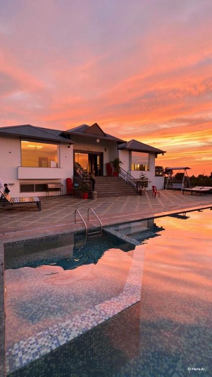 a house with a pool in front of a sunset at Infinity farm and garden in Bhopal