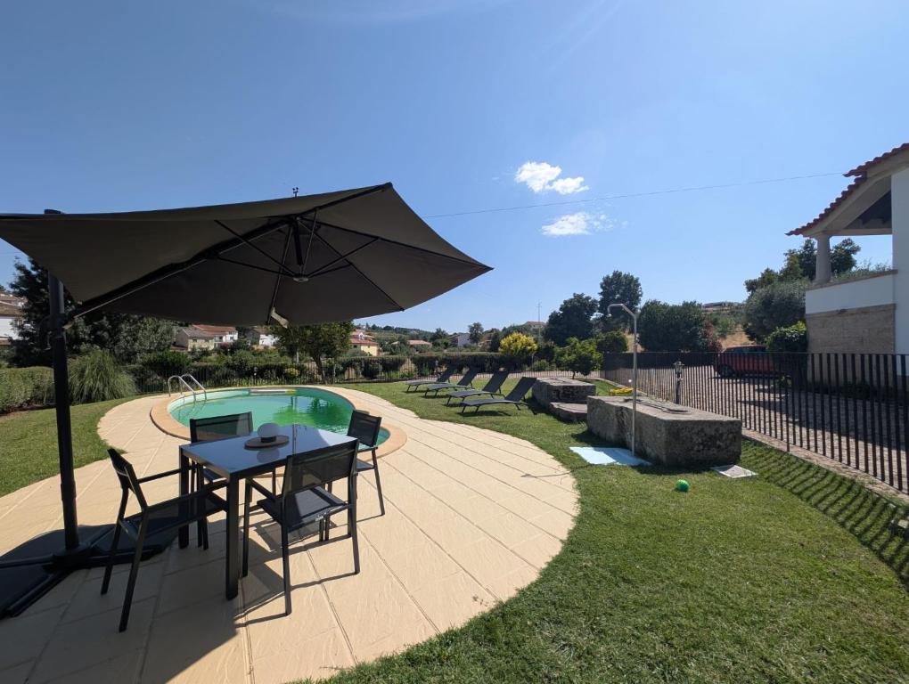 a patio with a table and an umbrella next to a pool at Casas Telhadas in Trancoso