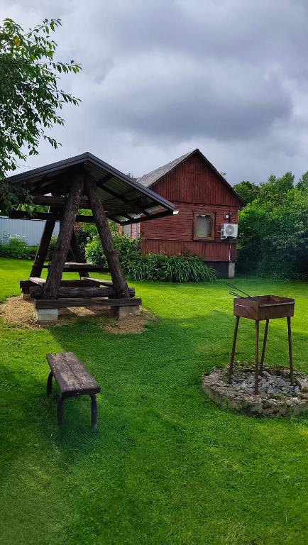 a picnic table and a bench in a yard at Vasarnīca Pie Anniņas in Pasteri